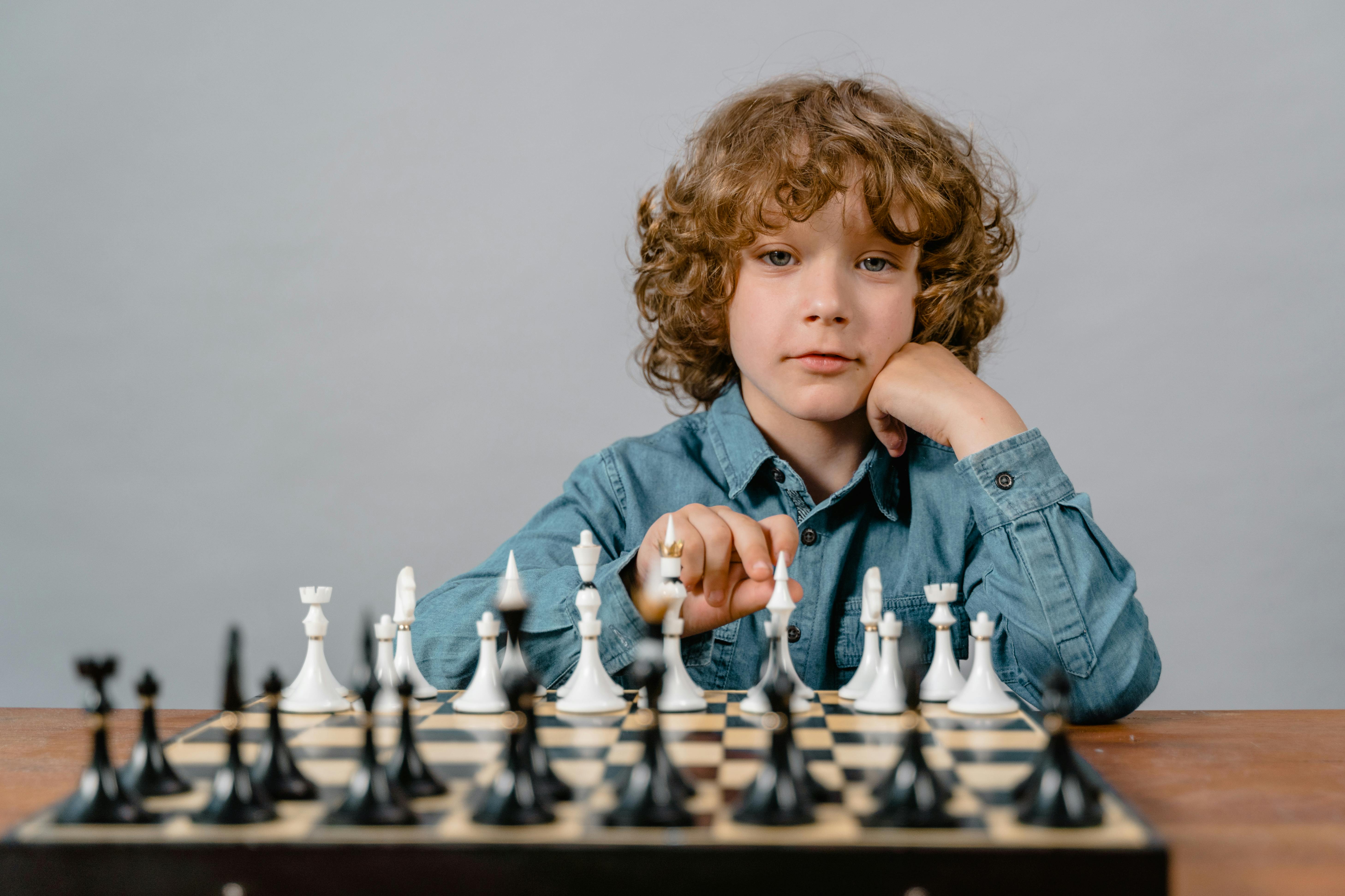 kid possing for a picture before the game of chess starts